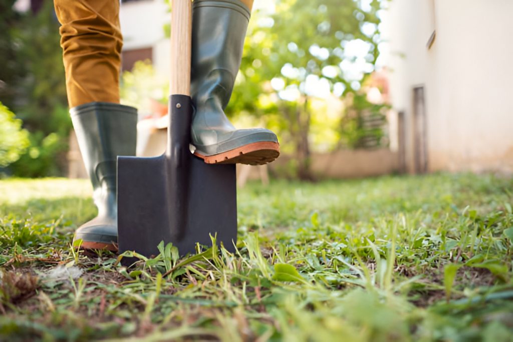 man pinning a shovel to the ground with his foot